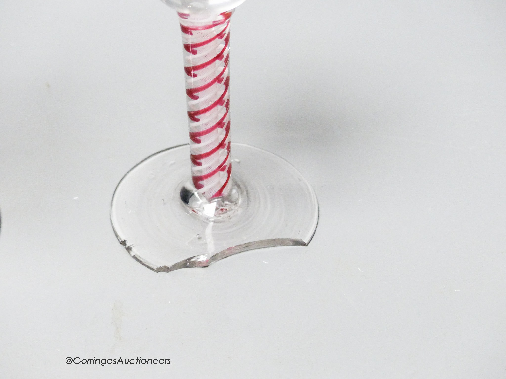 An early 18th century light baluster wine glass and an English red and white colour twist cordial glass, tallest 17.5cm